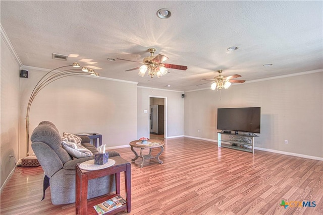 living area with light wood-type flooring, crown molding, and a textured ceiling