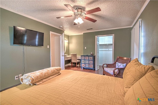 bedroom with a textured ceiling, wood finished floors, visible vents, and crown molding