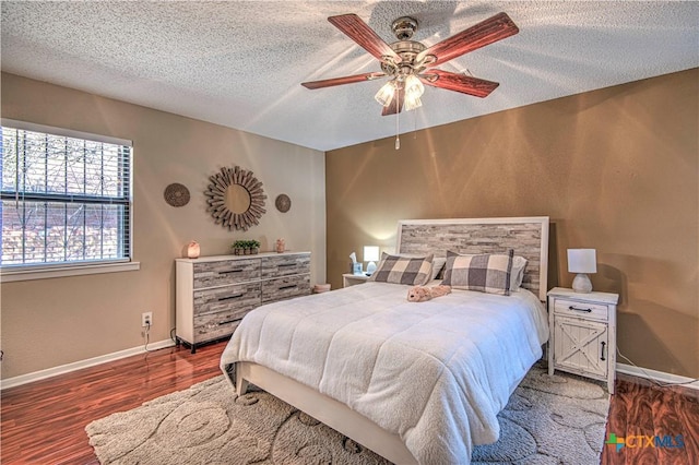 bedroom featuring a textured ceiling, ceiling fan, wood finished floors, and baseboards