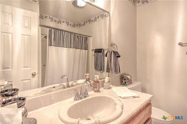 bathroom with curtained shower, a textured wall, toilet, a textured ceiling, and vanity