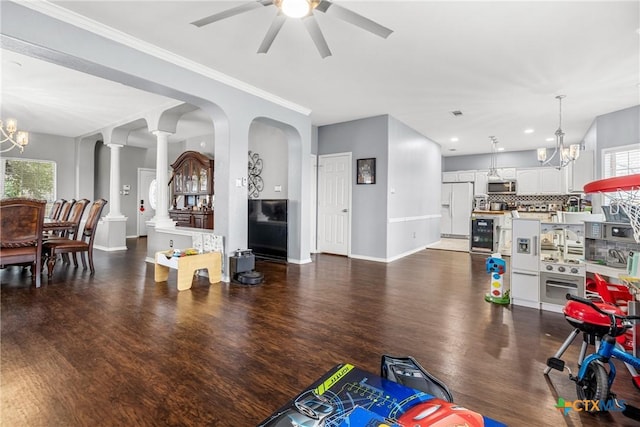 living room featuring ornate columns, baseboards, wood finished floors, and ceiling fan with notable chandelier