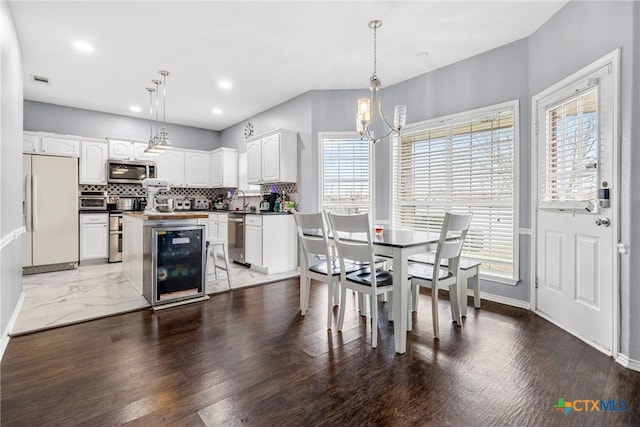 kitchen featuring beverage cooler, tasteful backsplash, dark countertops, a kitchen island, and appliances with stainless steel finishes