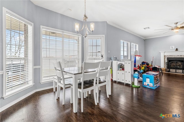 dining space with a fireplace, visible vents, ornamental molding, wood finished floors, and ceiling fan with notable chandelier