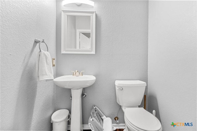 half bath featuring toilet and a textured wall