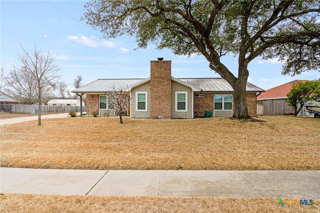 view of front of property with a chimney, metal roof, a standing seam roof, fence, and brick siding