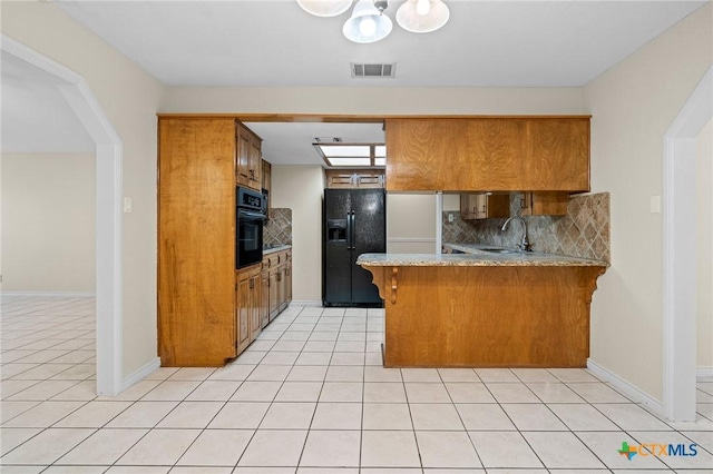 kitchen featuring tasteful backsplash, visible vents, a sink, a peninsula, and black appliances