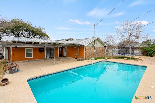 view of swimming pool featuring a trampoline, a fenced in pool, a patio area, and fence