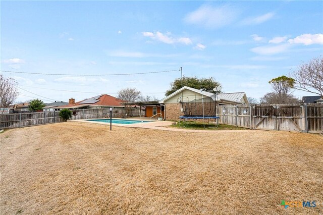 view of yard featuring a fenced backyard, a trampoline, a fenced in pool, and a patio