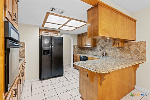 kitchen featuring a peninsula, a sink, visible vents, decorative backsplash, and black appliances