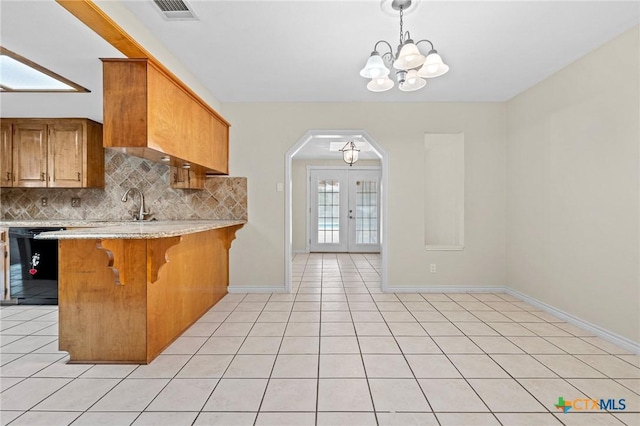 kitchen featuring arched walkways, black dishwasher, french doors, tasteful backsplash, and visible vents