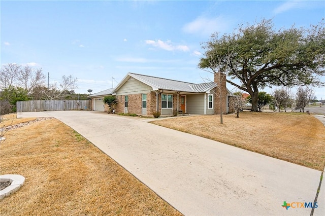 ranch-style home with a garage, concrete driveway, metal roof, fence, and brick siding