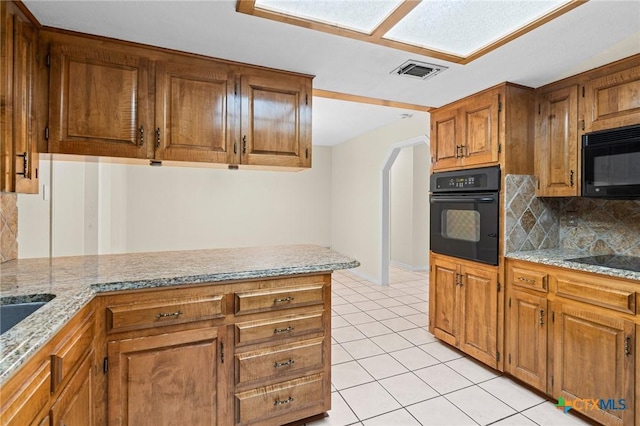 kitchen with brown cabinets, visible vents, black appliances, and light tile patterned flooring