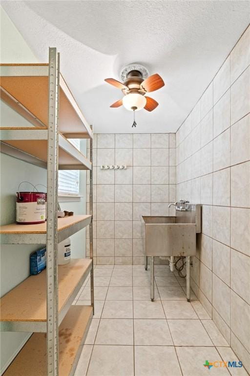 bathroom with a textured ceiling, a ceiling fan, tile walls, and tile patterned floors