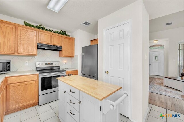 4602 Causeway Ct, Killeen, TX 76549 - kitchen featuring stainless steel appliances, under cabinet range hood, light tile patterned flooring, butcher block counters, and tasteful backsplash