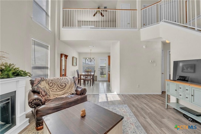 4602 Causeway Ct, Killeen, TX 76549 - living area with a high ceiling, light wood-style floors, a fireplace with raised hearth, a chandelier, and baseboards