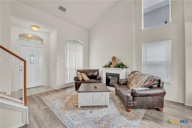 4602 Causeway Ct, Killeen, TX 76549 - living room with light wood-style floors, high vaulted ceiling, a glass covered fireplace, stairway, and baseboards