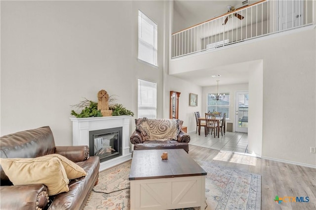 4602 Causeway Ct, Killeen, TX 76549 - living room with light wood-style floors, a towering ceiling, a glass covered fireplace, a chandelier, and baseboards