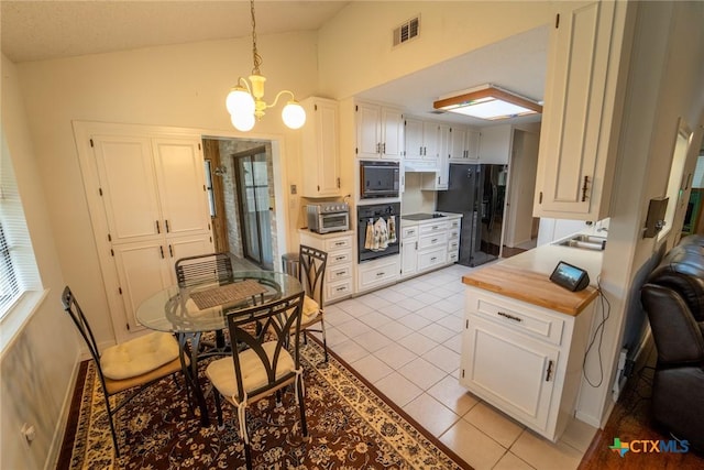 kitchen with black appliances, white cabinets, hanging light fixtures, lofted ceiling, and light tile patterned flooring