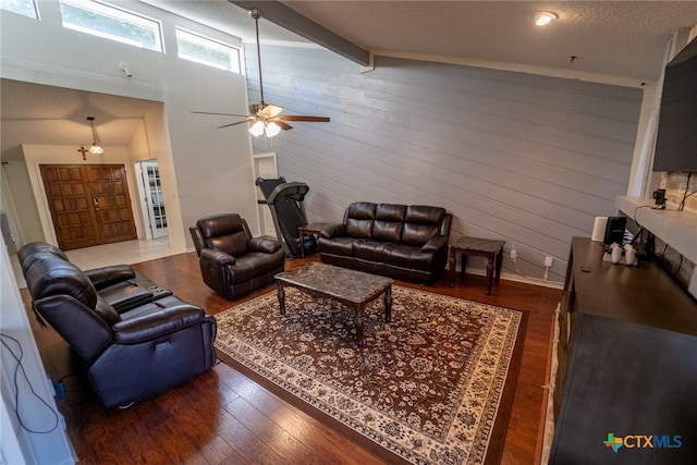 living room featuring a textured ceiling, ceiling fan, wood-type flooring, vaulted ceiling with beams, and wood walls