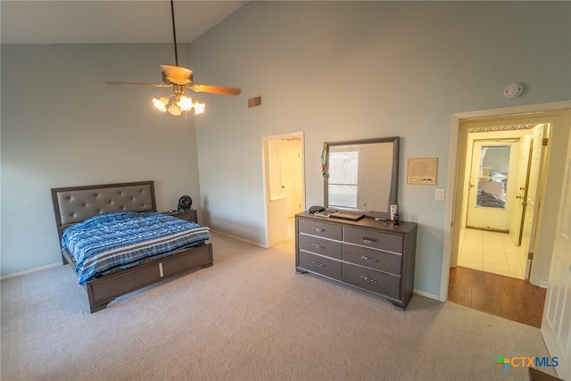 bedroom with ceiling fan, ensuite bathroom, high vaulted ceiling, and light carpet