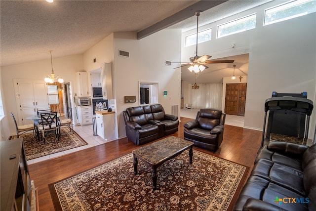 living room with ceiling fan with notable chandelier, a textured ceiling, light hardwood / wood-style floors, and high vaulted ceiling