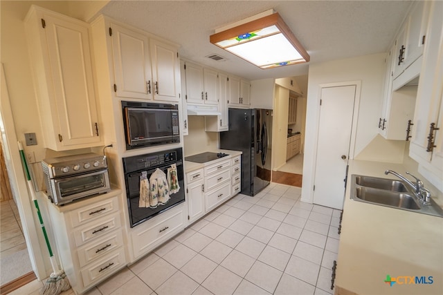 kitchen with light tile patterned floors, sink, white cabinetry, and black appliances