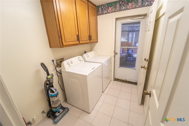 washroom with cabinets, light tile patterned floors, and washer and clothes dryer