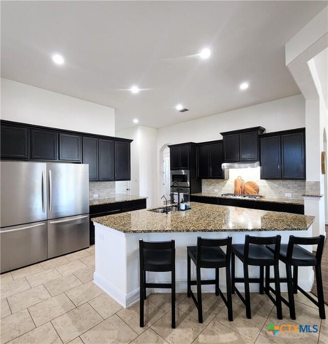 555 Solms Frst, New Braunfels, TX 78132 - kitchen with appliances with stainless steel finishes, dark stone counters, tasteful backsplash, dark cabinetry, and a sink