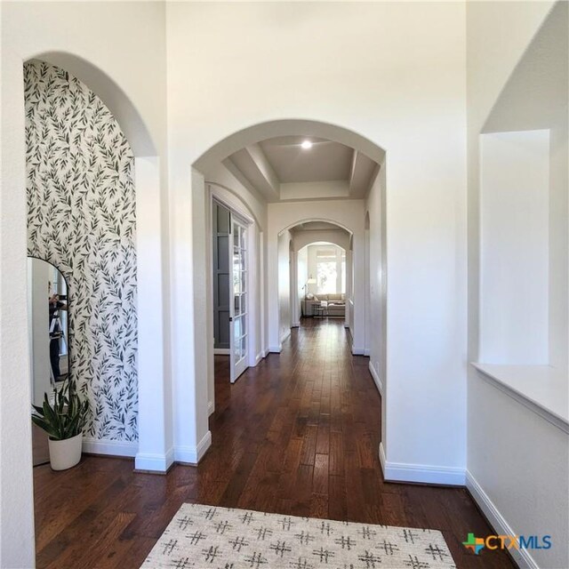 555 Solms Frst, New Braunfels, TX 78132 - hallway featuring a raised ceiling, hardwood / wood-style flooring, baseboards, arched walkways, and wallpapered walls