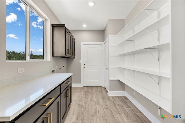 interior space with hookup for an electric dryer, light hardwood / wood-style floors, washer hookup, and cabinets