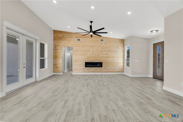 unfurnished living room with wooden walls, light hardwood / wood-style flooring, and vaulted ceiling