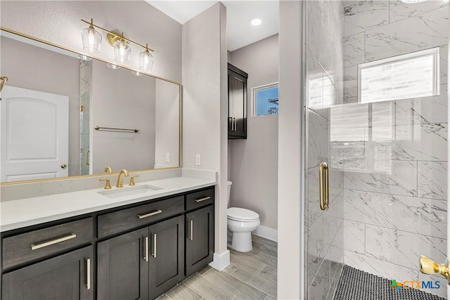 bathroom featuring vanity, toilet, a shower with door, and wood-type flooring