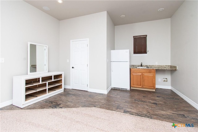 2241 Berger Rd, Temple, TX 76501 - kitchen with freestanding refrigerator, a sink, baseboards, dark wood-style floors, and light stone counters