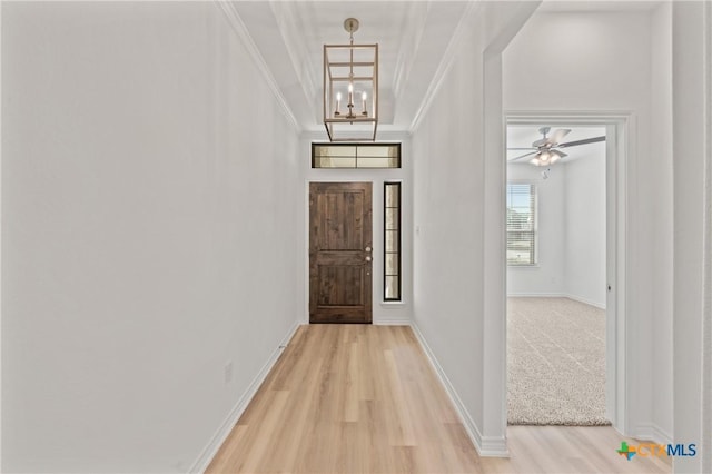 foyer entrance with ceiling fan with notable chandelier, light wood-type flooring, and ornamental molding