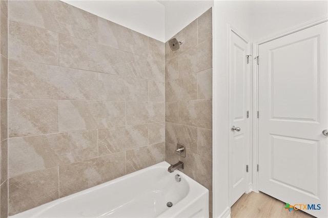 bathroom with hardwood / wood-style floors and tiled shower / bath combo