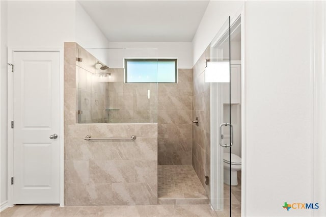 bathroom with tile patterned floors, toilet, and a shower with shower door