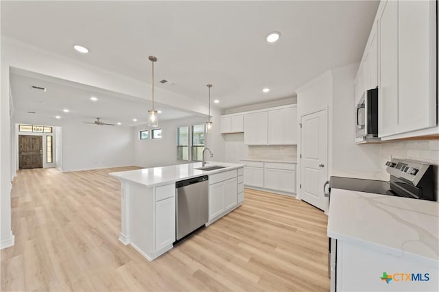 kitchen with light wood-type flooring, stainless steel appliances, sink, white cabinets, and an island with sink