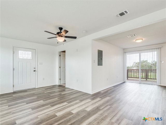 unfurnished living room featuring ceiling fan, electric panel, and light hardwood / wood-style flooring