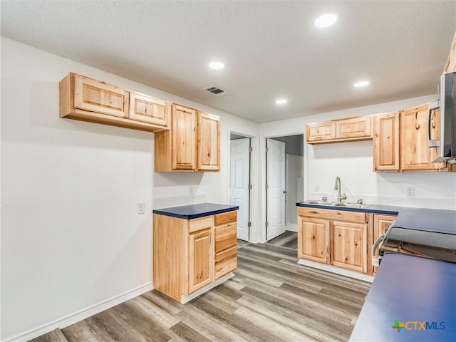 kitchen featuring a textured ceiling, dark hardwood / wood-style floors, light brown cabinets, and sink