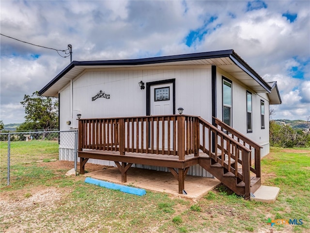 rear view of property featuring a lawn and a deck