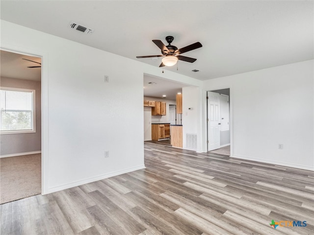 unfurnished living room featuring ceiling fan and light hardwood / wood-style floors