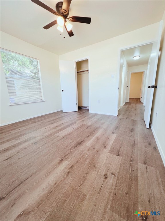 unfurnished bedroom featuring light hardwood / wood-style floors, ceiling fan, and a closet