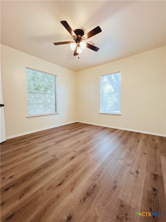 unfurnished room featuring plenty of natural light, hardwood / wood-style flooring, and ceiling fan