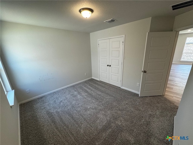 unfurnished bedroom with dark colored carpet and a closet