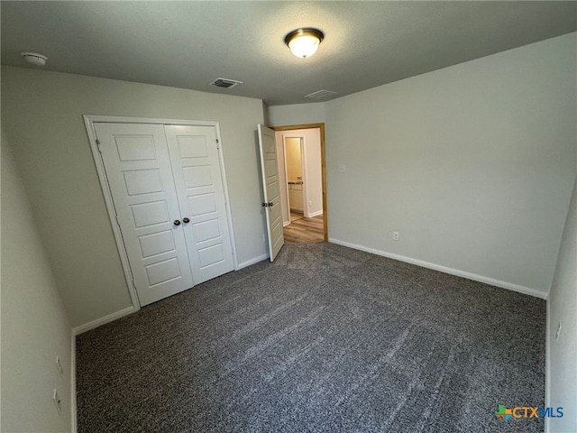 unfurnished bedroom with dark colored carpet and a closet