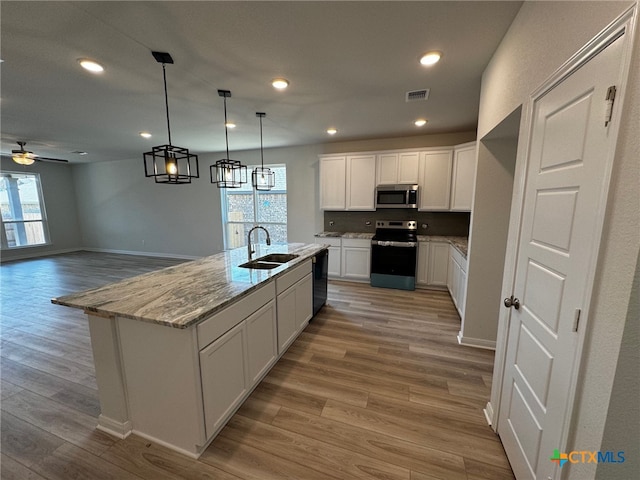 kitchen with white cabinets, a healthy amount of sunlight, a center island with sink, and appliances with stainless steel finishes