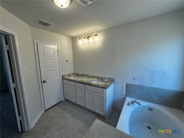 bathroom featuring a tub to relax in, vanity, and a textured ceiling