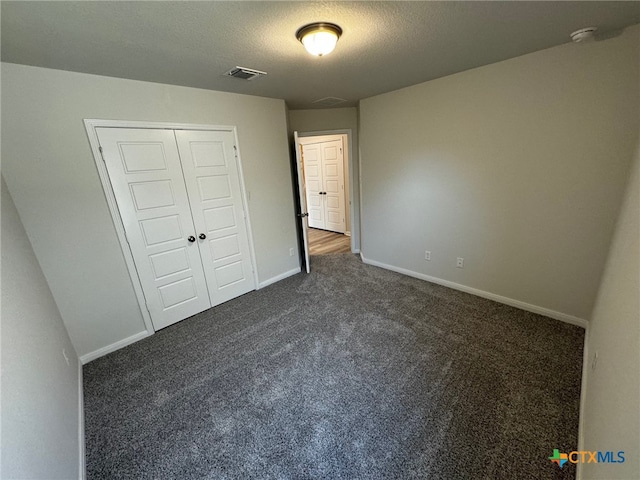 unfurnished bedroom with a closet, a textured ceiling, and dark colored carpet