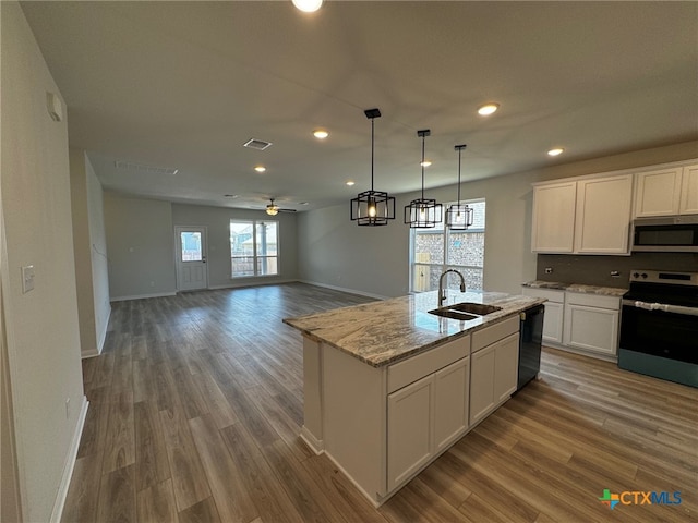 kitchen featuring a center island with sink, sink, hardwood / wood-style flooring, white cabinetry, and appliances with stainless steel finishes