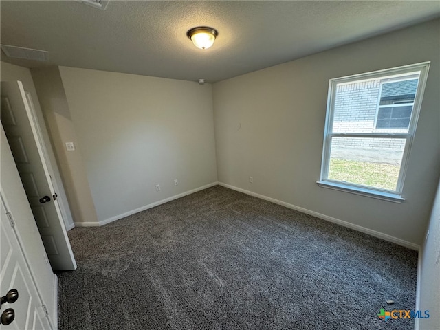 empty room with a textured ceiling and dark carpet